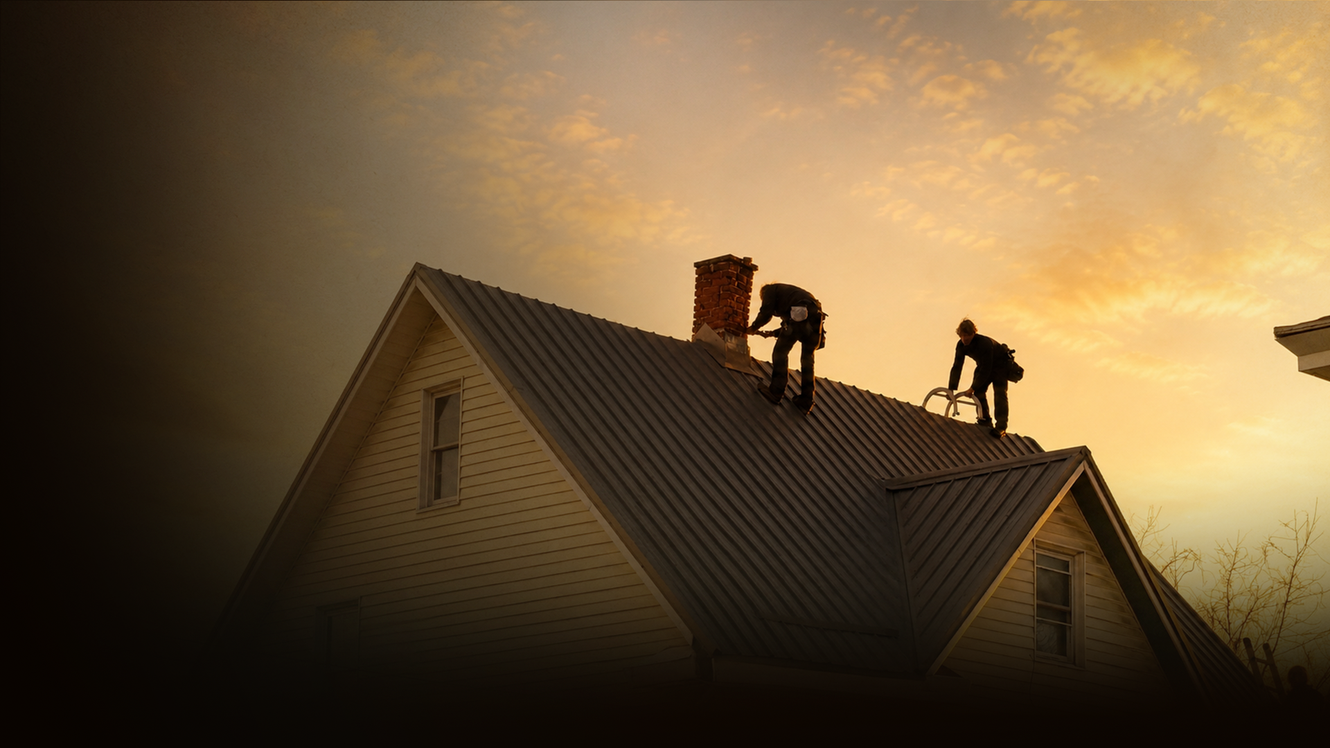Roofing crew on a standing-seam metal roof at golden hour